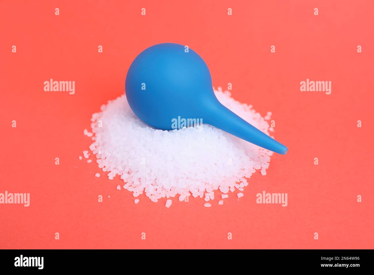 Enema and heap of salt on coral background. Medical treatment Stock