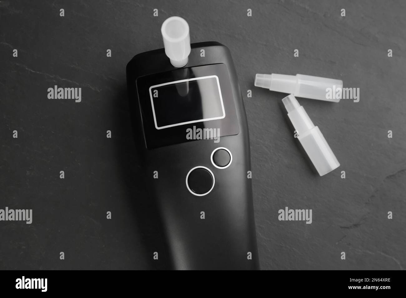 Modern breathalyzer and mouthpieces on black background, flat lay Stock