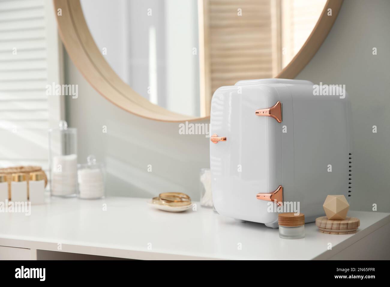 Cosmetics refrigerator and skin care products on white vanity table