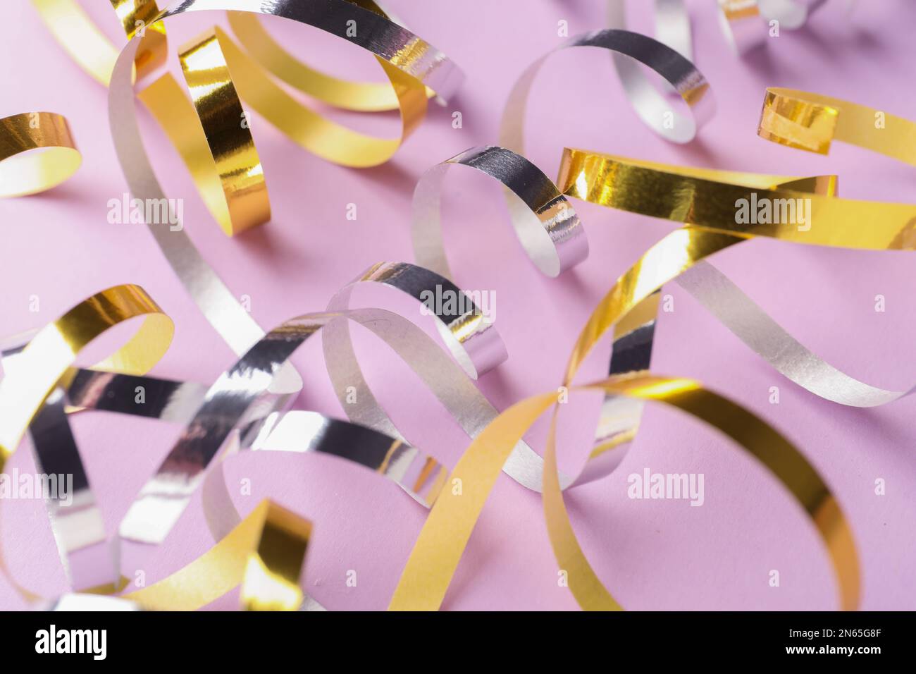 Shiny serpentine streamers on lilac background, closeup Stock Photo - Alamy