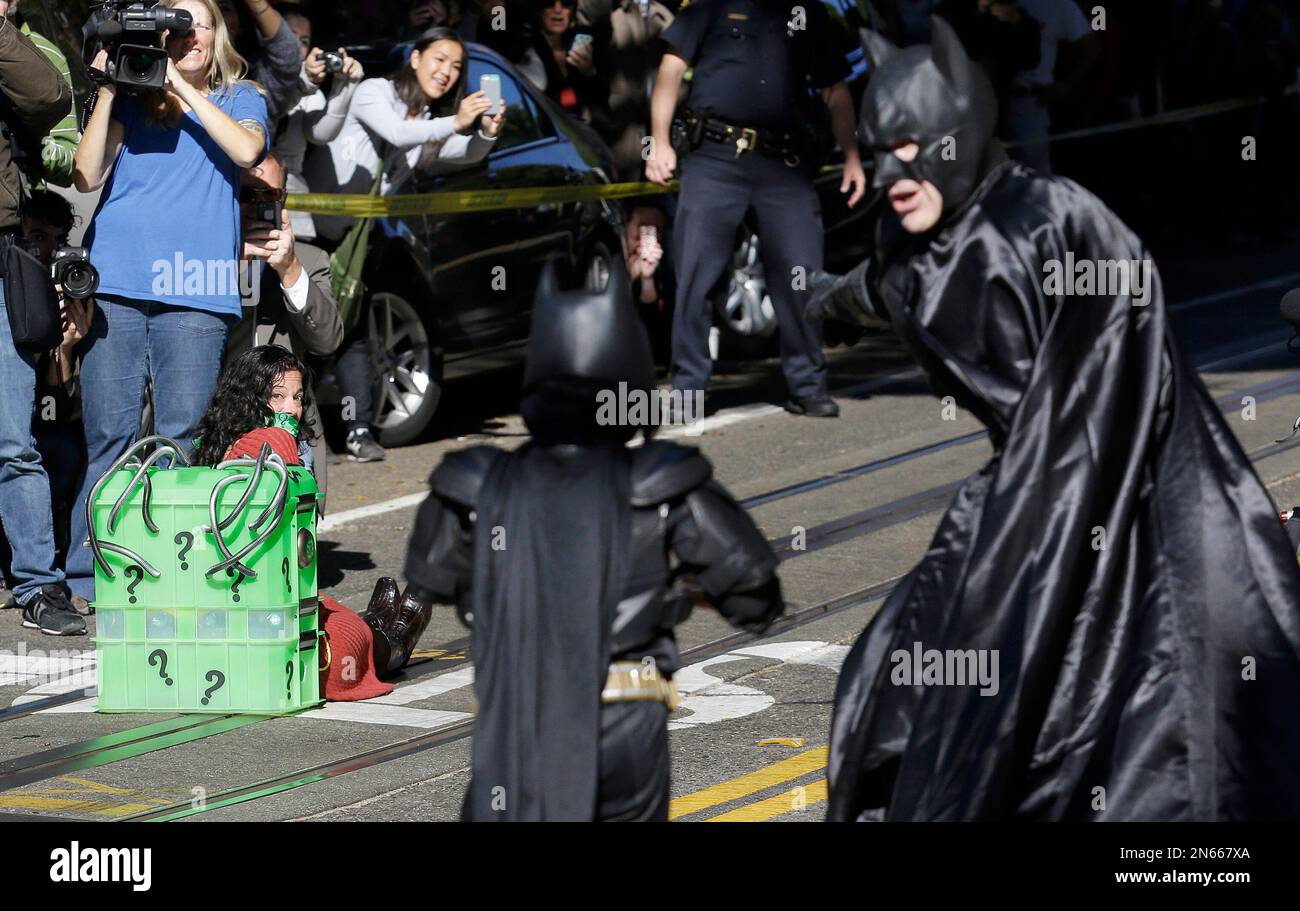 Miles Scott, dressed as Batkid, center, walks with Batman to save a damsel  in distress on the Cable Car line in San Francisco, Friday, Nov. 15, 2013.  San Francisco turned into Gotham