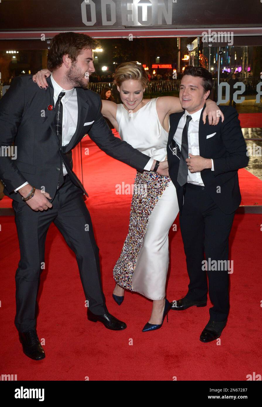 Actors Liam Hemsworth, Jennifer Lawrence and Josh Hutcherson play together  on the red carpet as they prepare to pose for photographers at the World  Premiere of 'The Hunger Games: Catching Fire', on, image size:895x1390