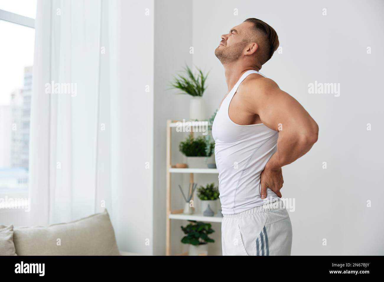Man sports back pain after working out at home, pumped up man works out