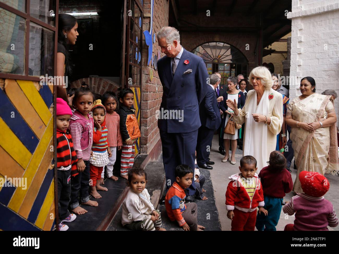 Britain's Prince Charles looks at children as his wife Camilla, the Duchess of Cornwall, speaks with a school official at Katha Lab School, a school for underprivileged children, in New Delhi, India, Friday, Nov. 8, 2013. Charles and Camilla are on a nine-day visit to India. (AP Photo/Saurabh Das) Stock Photo