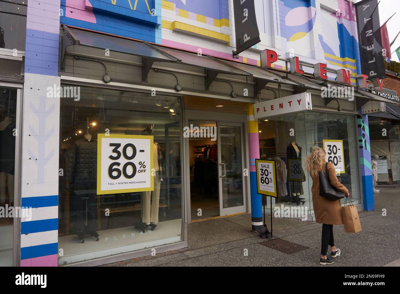 Young woman carrying a shopping bag walking past Plenty women's