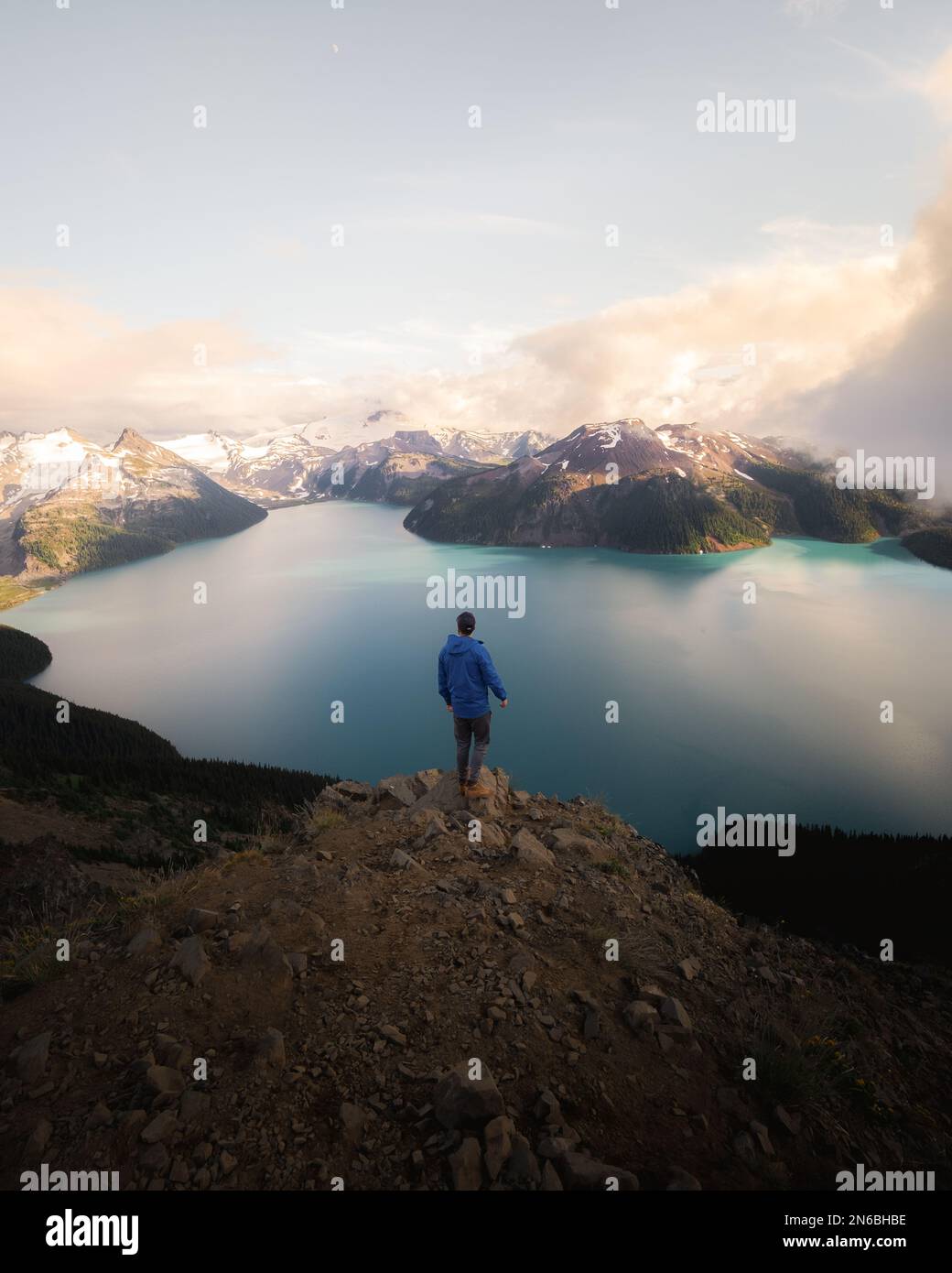 man standing on mountain peak looking out at the scenery Stock Photo