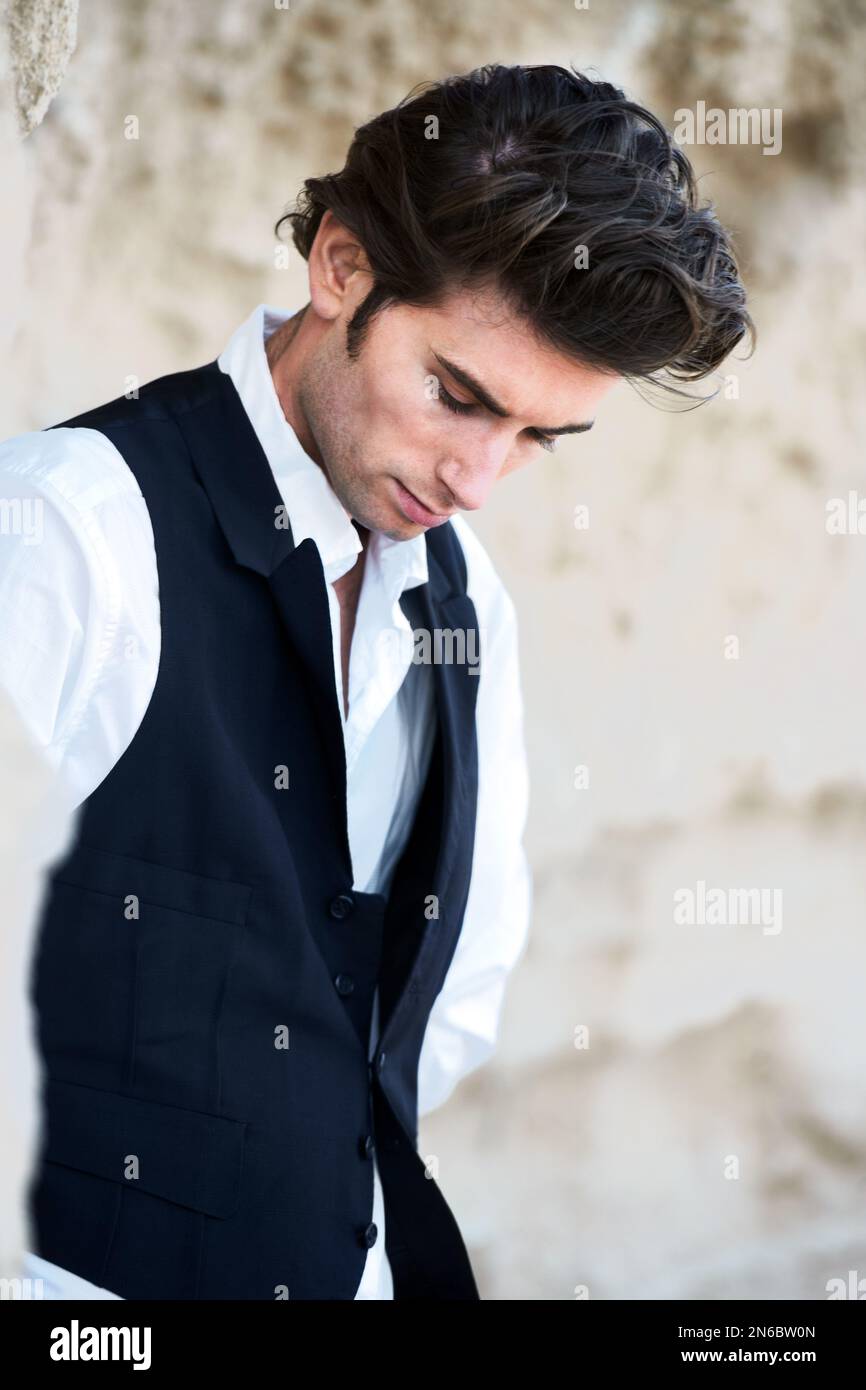 Tall, dark and brooding. Closeup of a handsome young male wearing a vest and looking downwards. Stock Photo