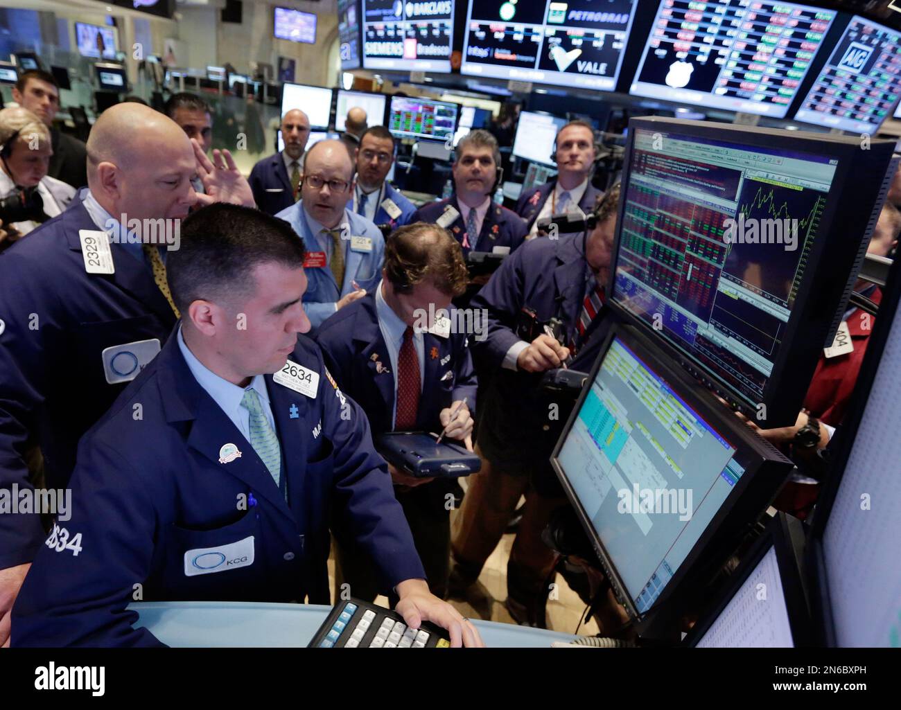 Specialists Michael O'Connor, left, and Matthew Diez, foreground left, work with traders at the post that handles US Steel, on the floor of the New York Stock Exchange Thursday, Oct. 17, 2013. Weak earnings from IBM and other major U.S. companies are dragging the stock market lower in early trading. (AP Photo/Richard Drew) Stock Photo