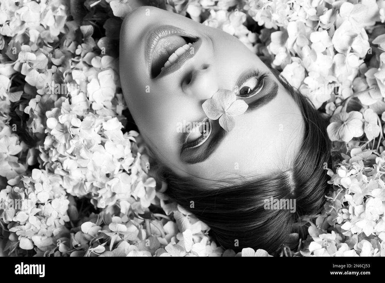 Nature beauty. Funny Woman lying on flowers. Unity with nature. Blossom