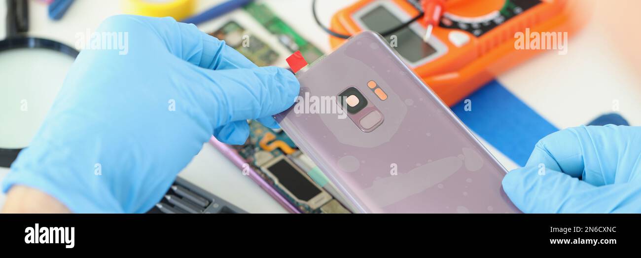 Technician repairs broken smartphone at table in workshop Stock Photo