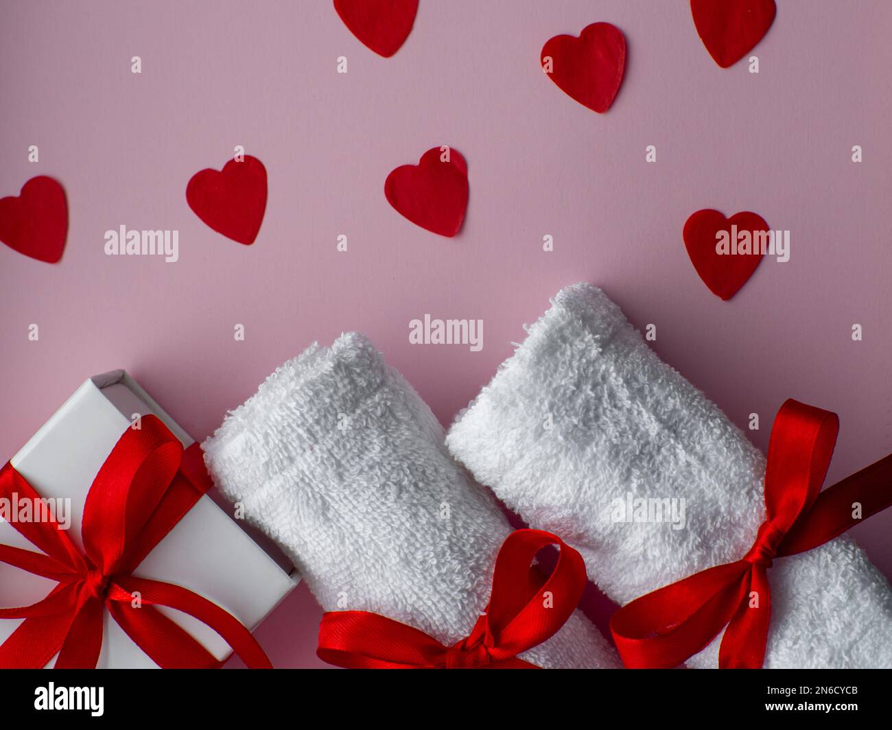 Flat lay with tiny heartshaped papers, two white towels and gift box
