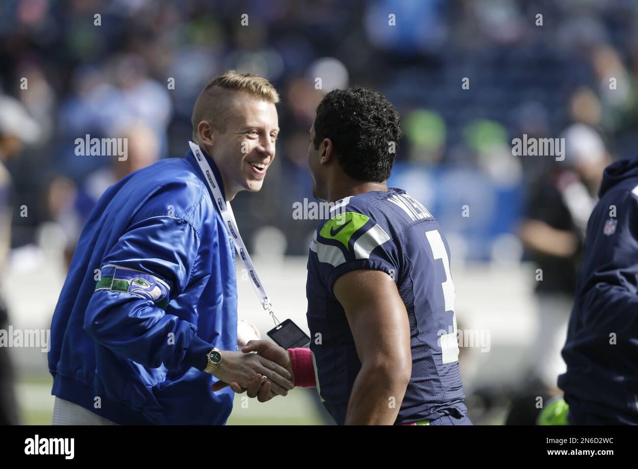 Seattle hip hop and rap singer Macklemore greets Seattle Seahawks  quarterback Russell Wilson before an NFL football game between the Seahawks  and Tennessee Titans, Sunday, Oct. 13, 2013, in Seattle. (AP Photo/Elaine