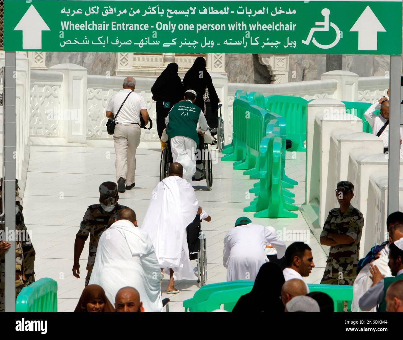 Muslim pilgrims on wheelchairs and one each pass through a