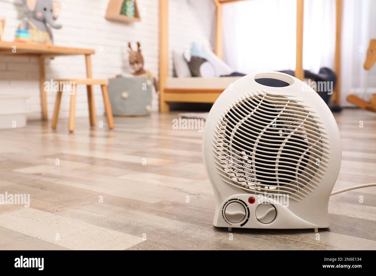 Modern electric fan heater on floor at home. Space for text Stock Photo