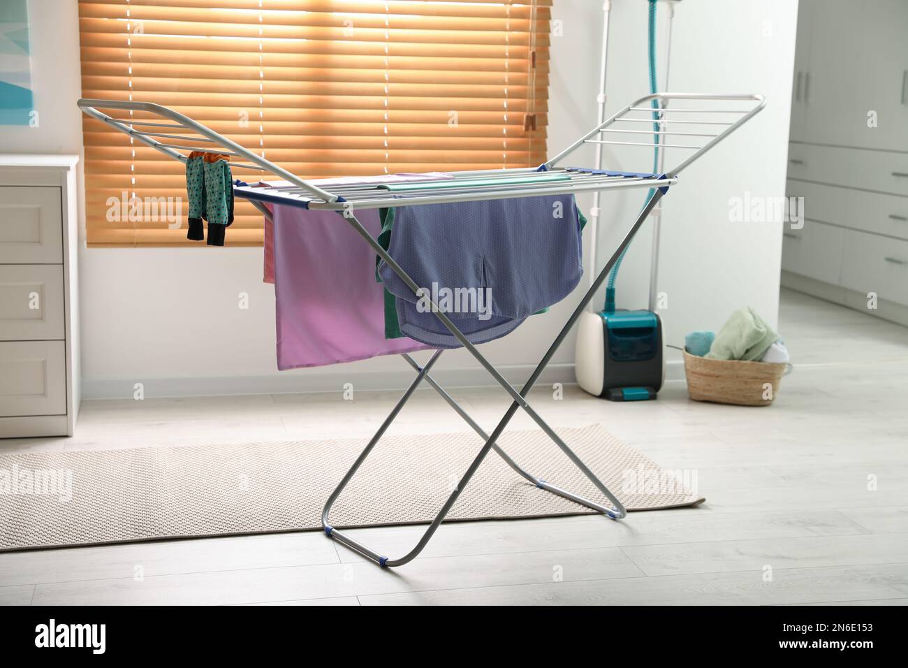 Clean laundry hanging on drying rack indoors Stock Photo