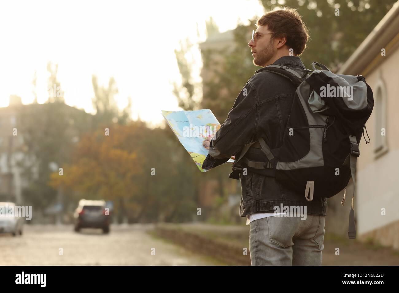 Traveler with world map on city street, back view Stock Photo - Alamy