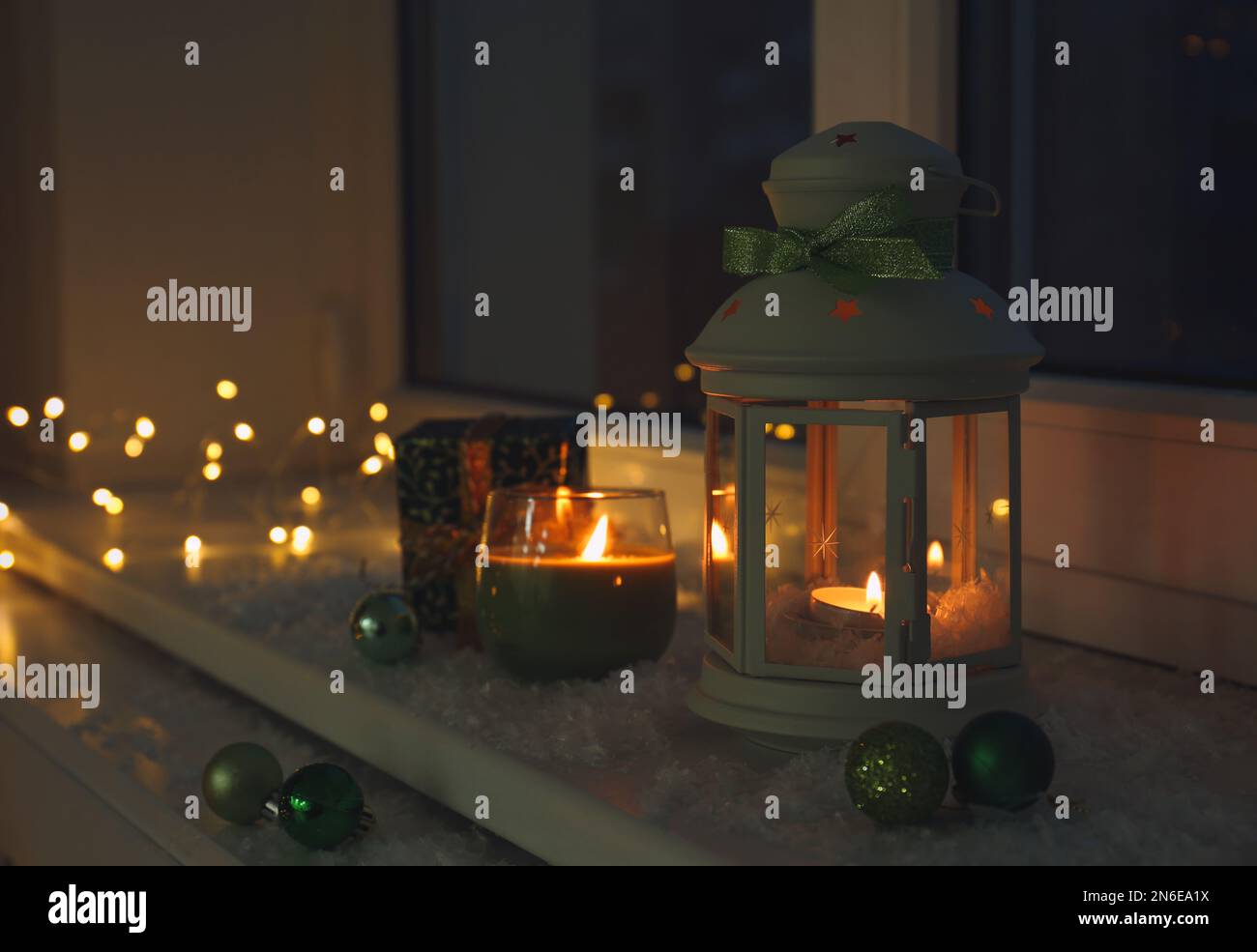 Beautiful Christmas lantern and other decorations on snowy window sill ...
