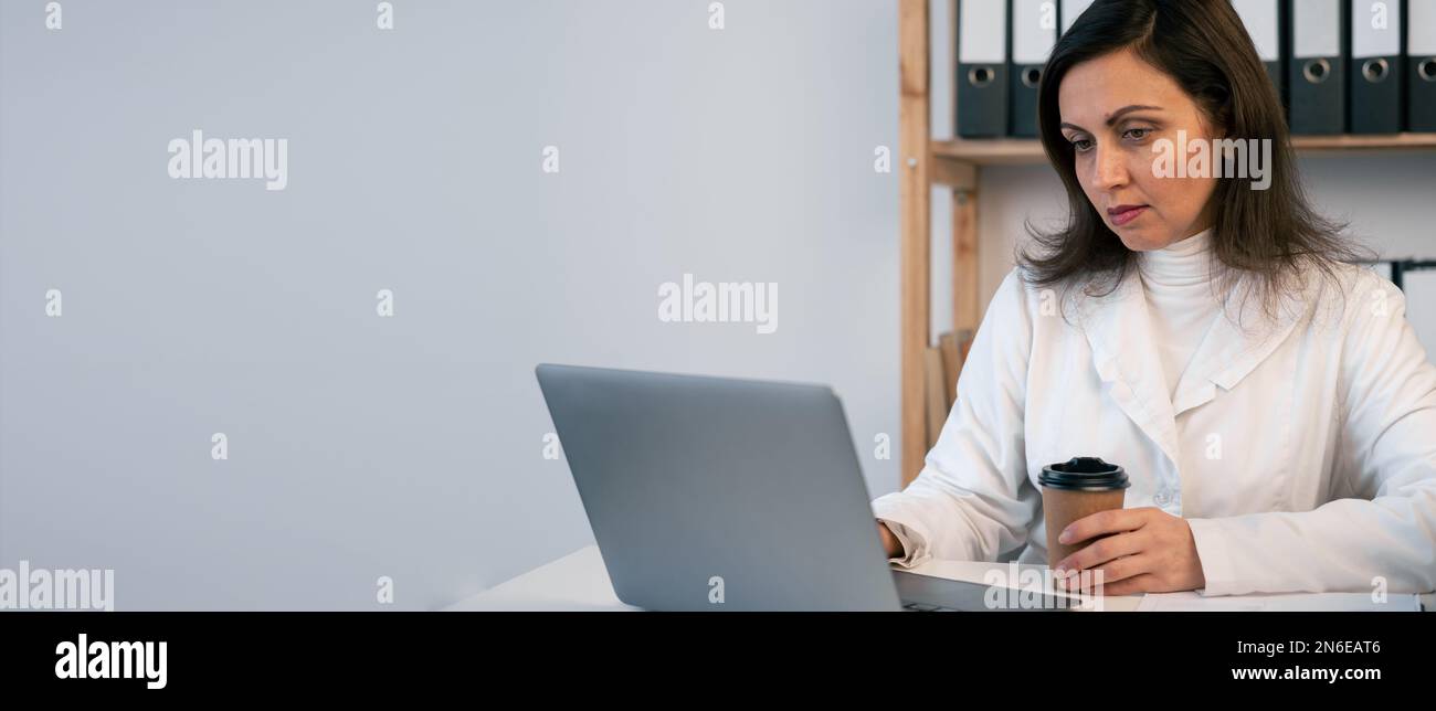 Busy Indian female doctor drinking coffee tea having break while