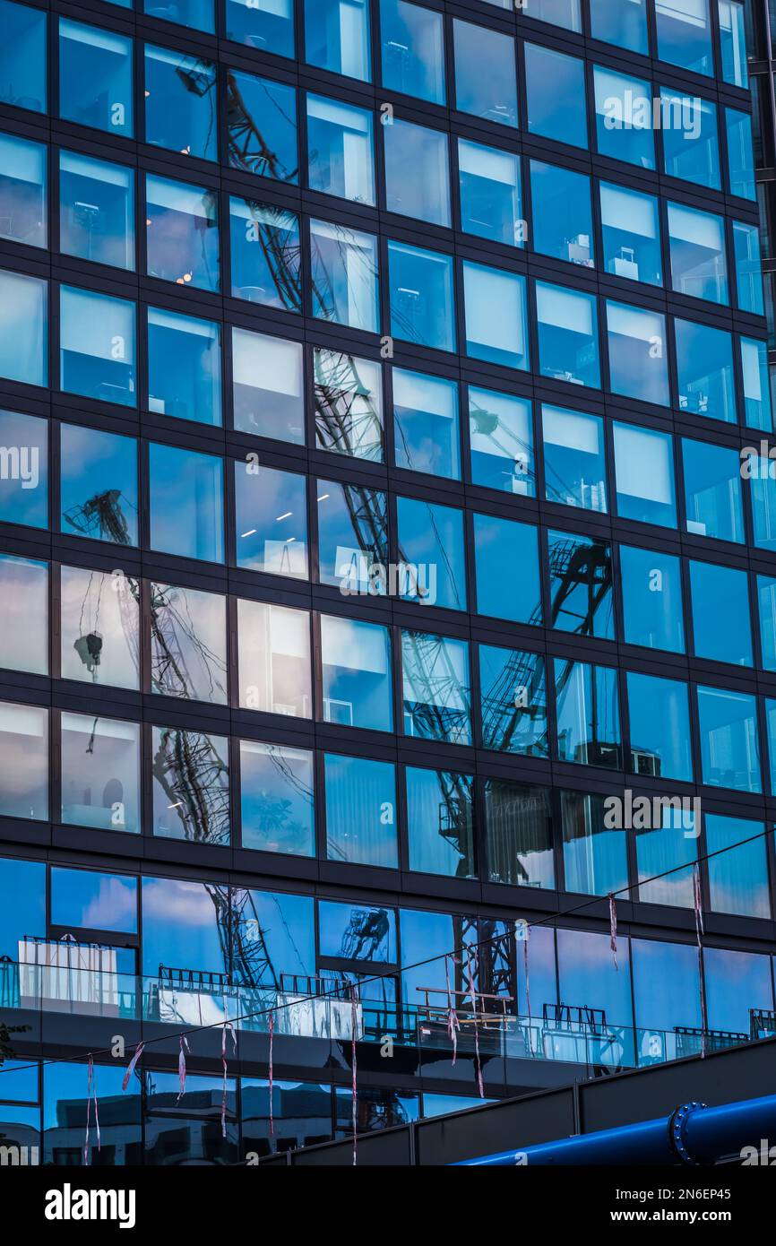 Glass facade of a modern office building reflecting the blue sky and ...