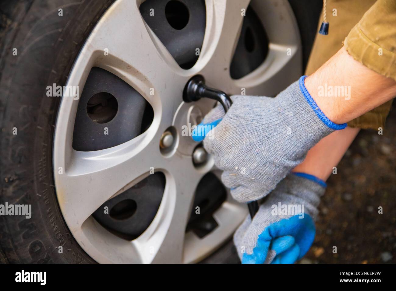 Hyundai wheel change, car is jacked up. Male hands unscrews wheel