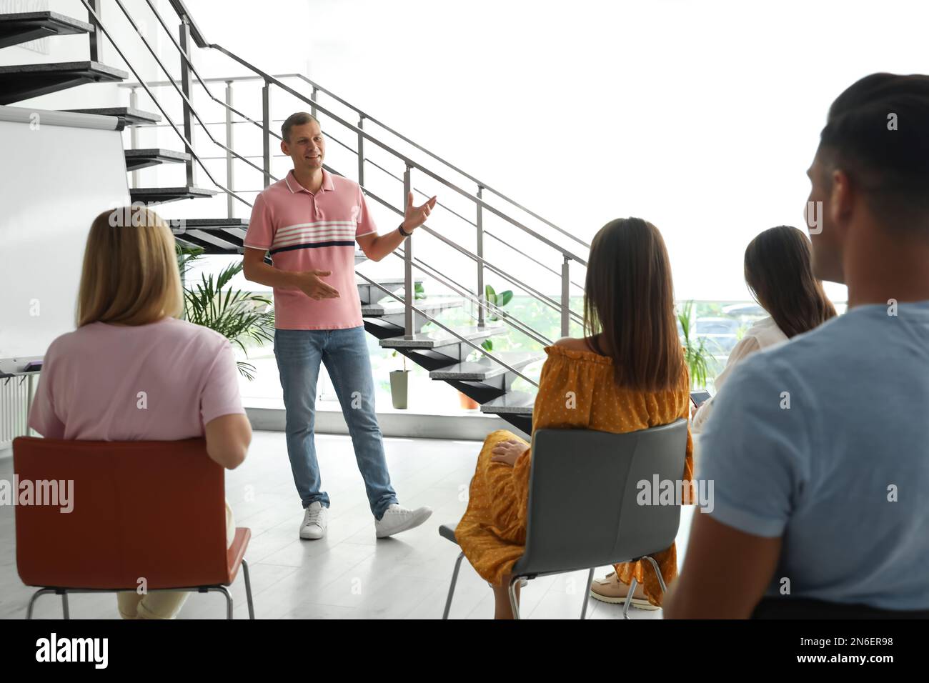 Male lecturer in casual clothes talking to audience indoors Stock Photo
