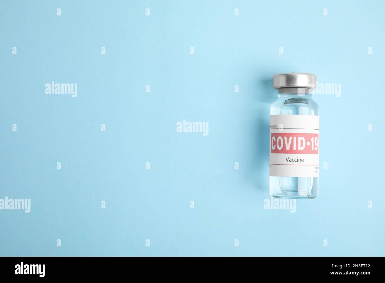 Vial with coronavirus vaccine on light blue background, top view. Space ...