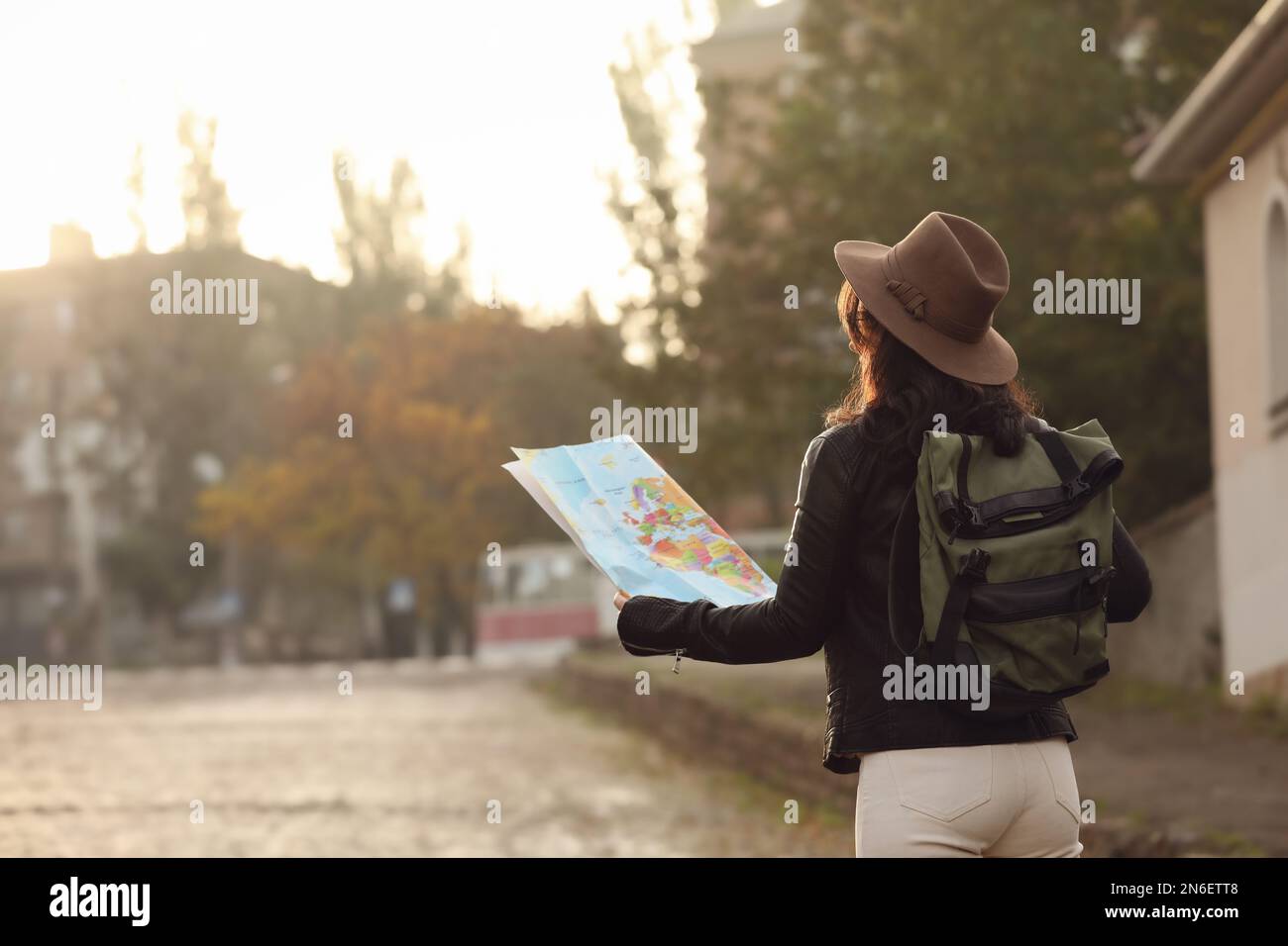 Traveler with map and backpack on city street, back view Stock Photo ...