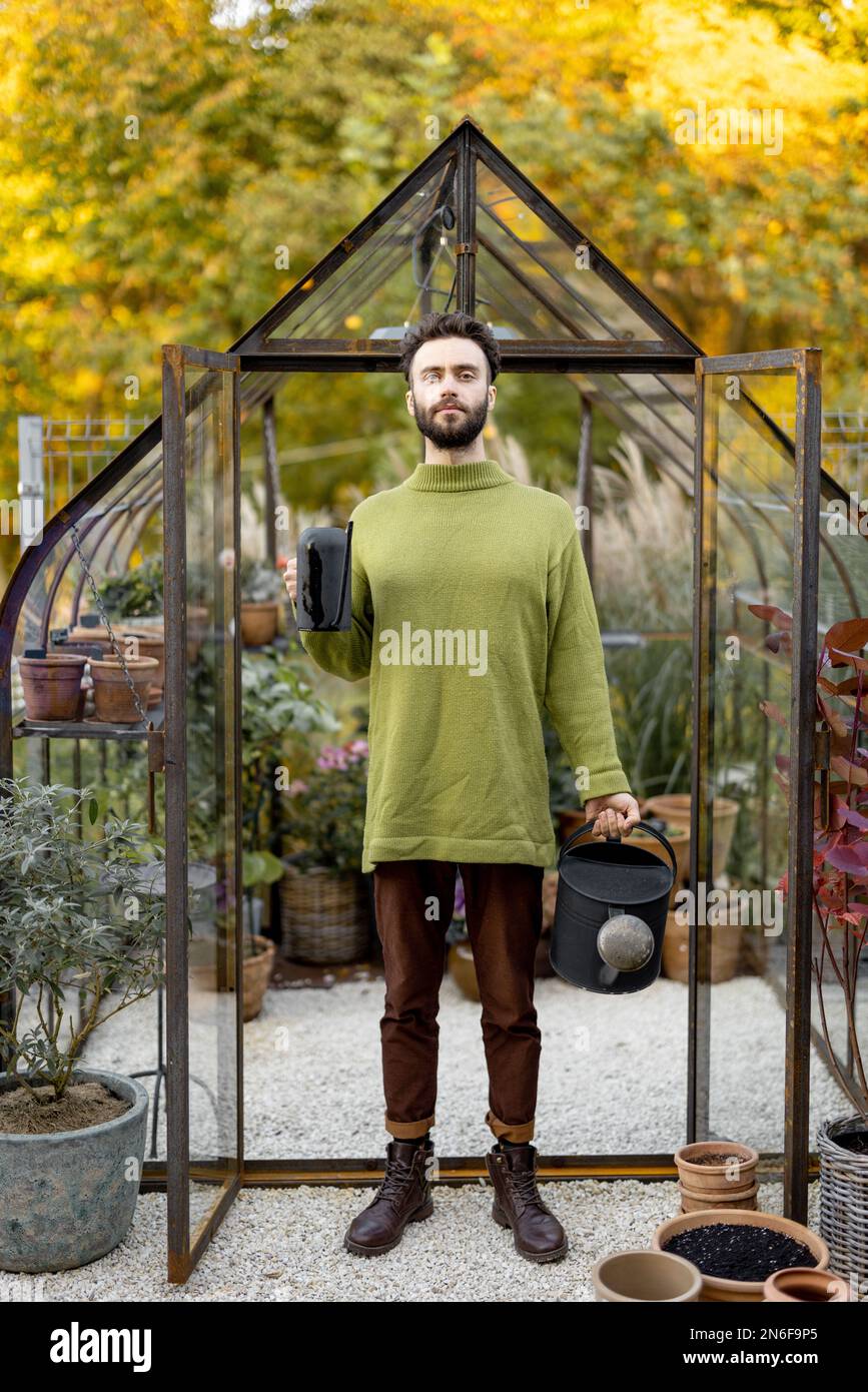 Stylish guy with watering can in garden Stock Photo