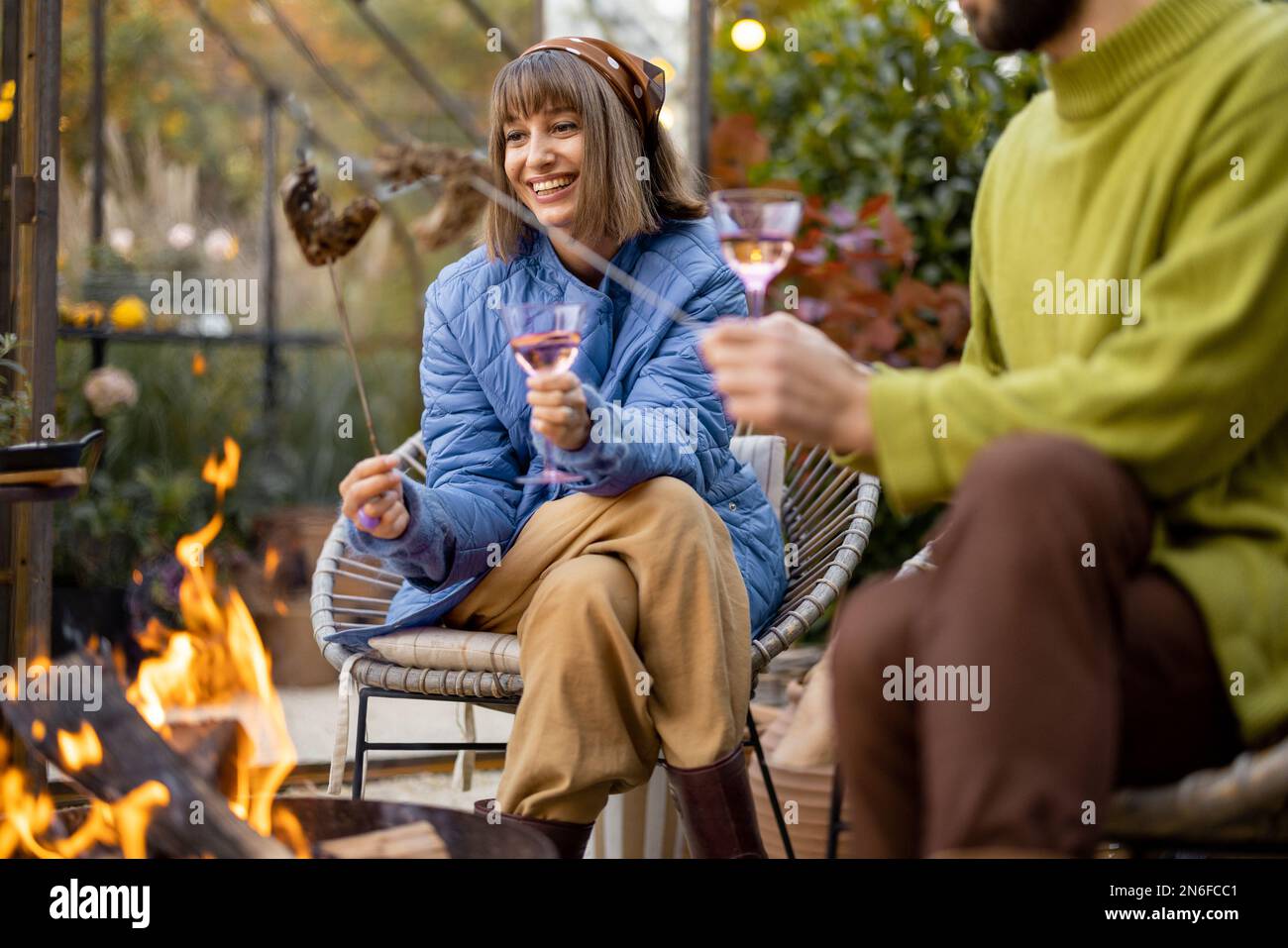 Young couple spending dinner time by the fire at backyard Stock Photo