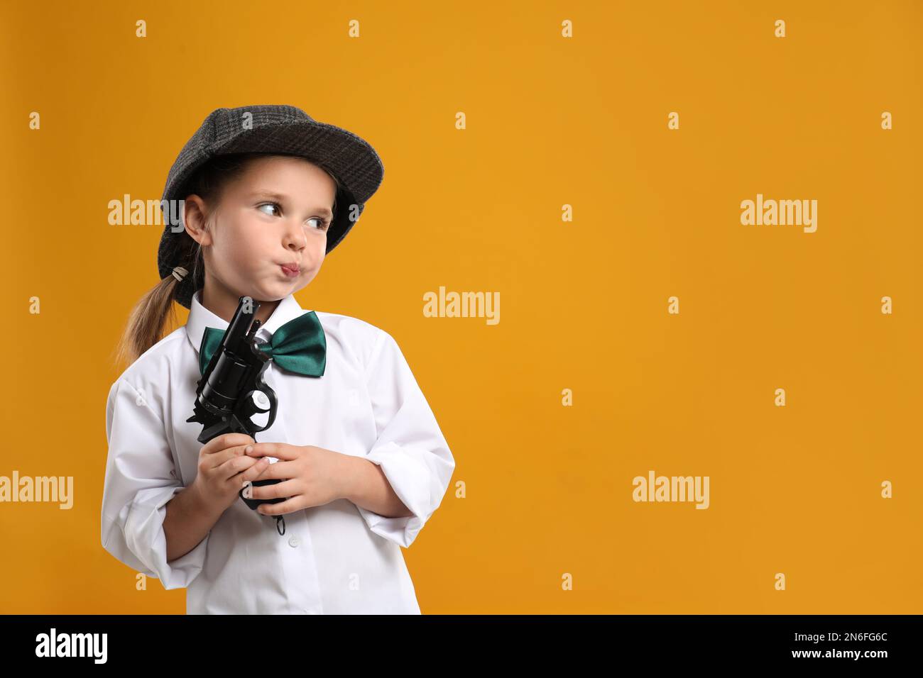 Cute little detective with revolver on yellow background. Space for text Stock Photo