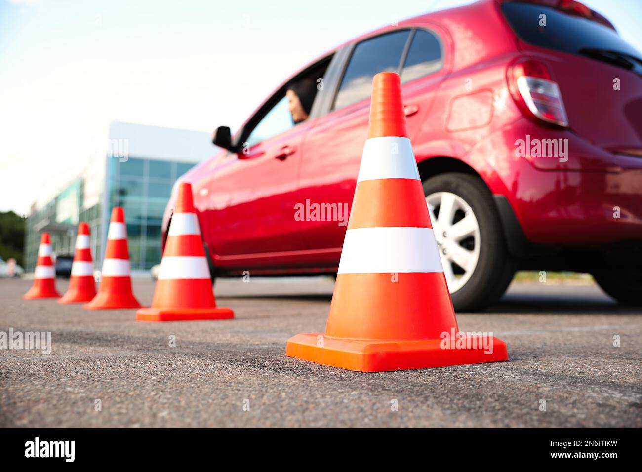 Traffic cones near red car outdoors. Driving school exam Stock Photo