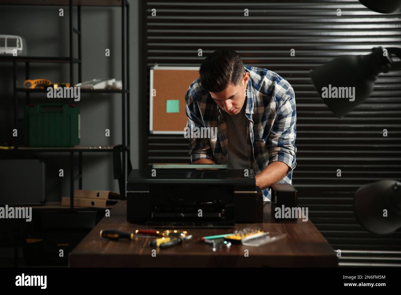 Professional repairman fixing modern printer in office Stock Photo
