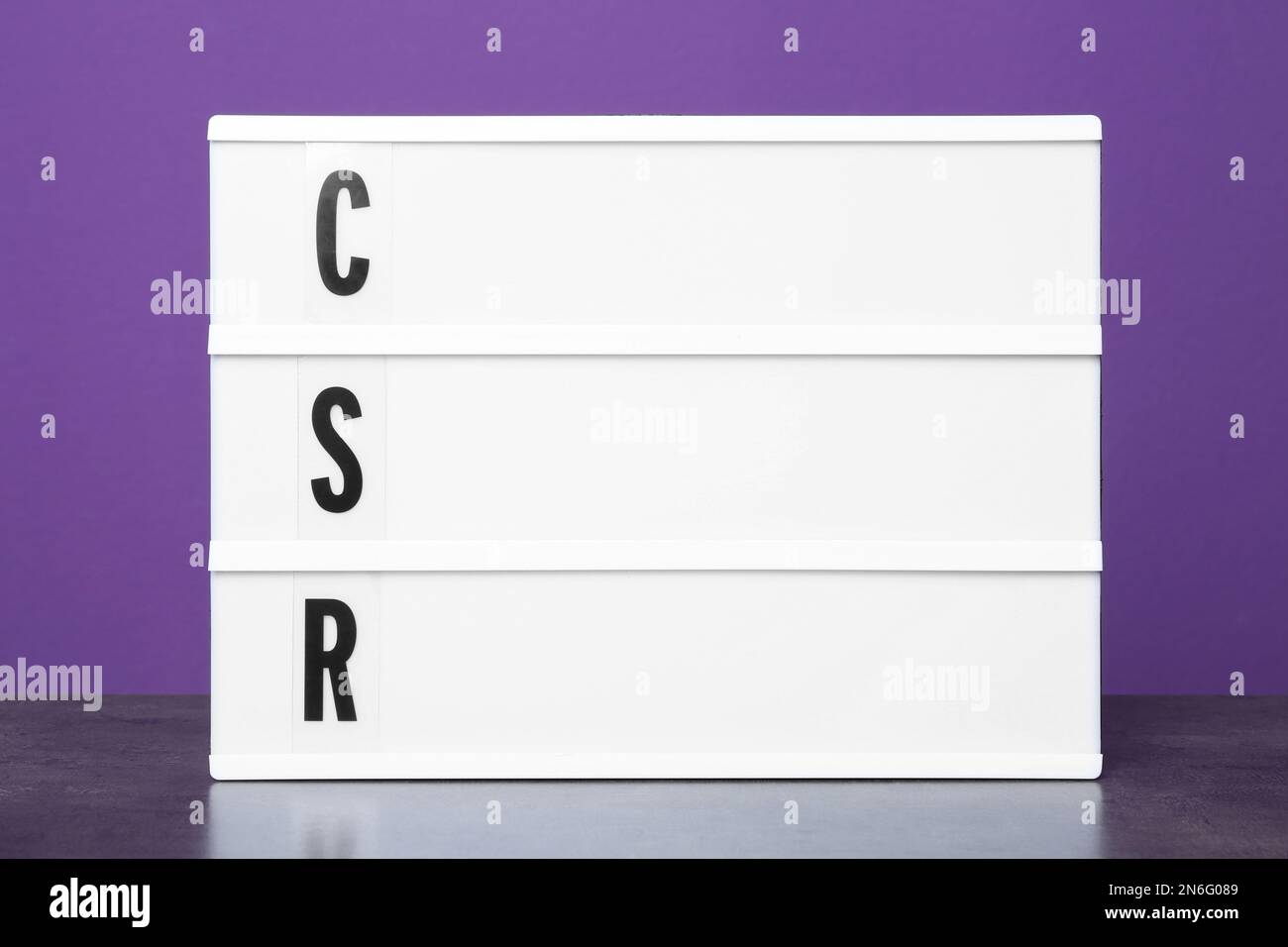 Light box with letters CSR on table against purple background ...