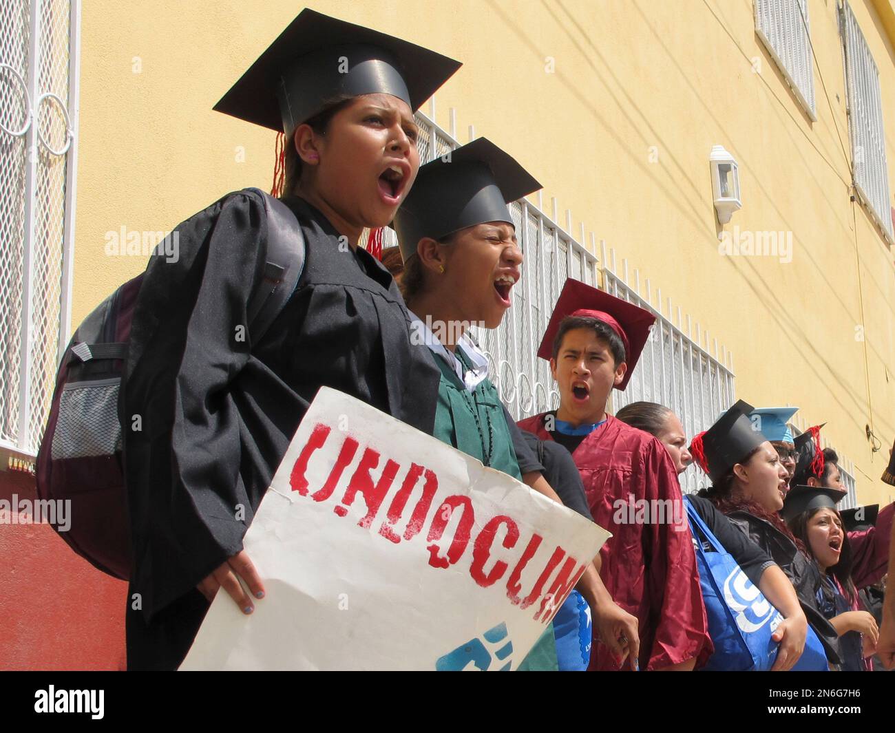 Wearing graduation-style caps and gowns, Mexican youth raised in the U.S,  chant slogans outside a migrant shelter before crossing the international  bridge from Nuevo Laredo, Mexico, Monday Sept. 30, 2013. Wearing a
