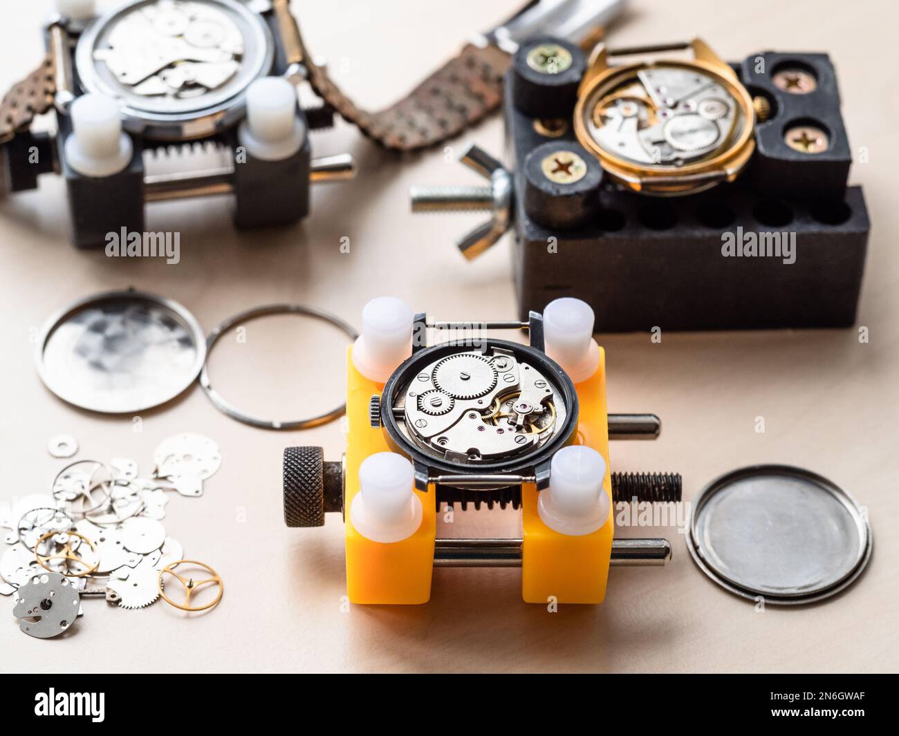 open mechanical watches in holders on wooden table in watchmaker workshop Stock Photo