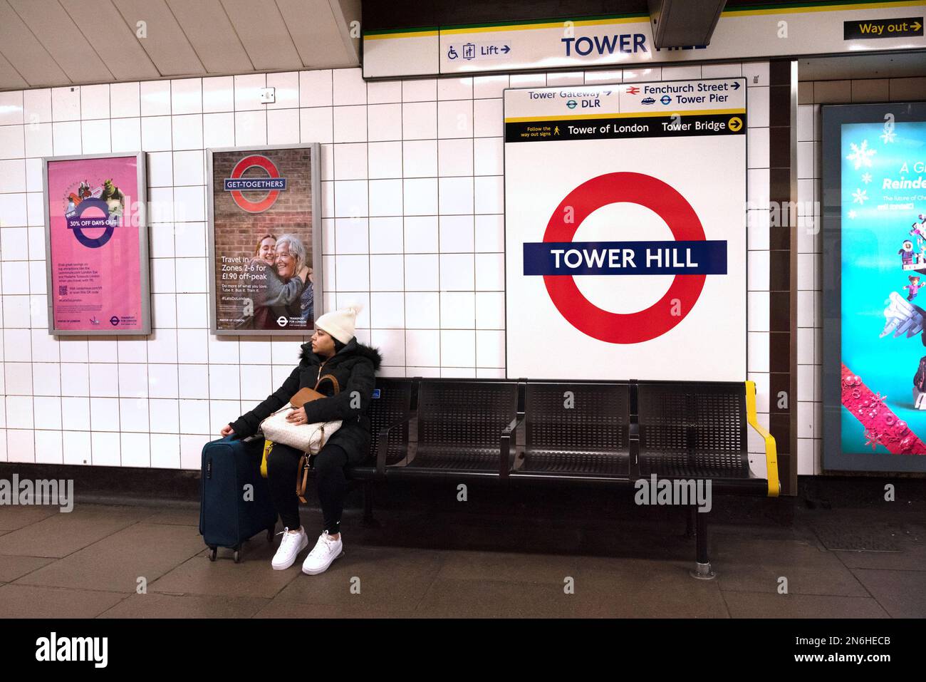 London, England, UK. Woman sitting on a bench on the platform of Tower Hill underground station Stock Photo