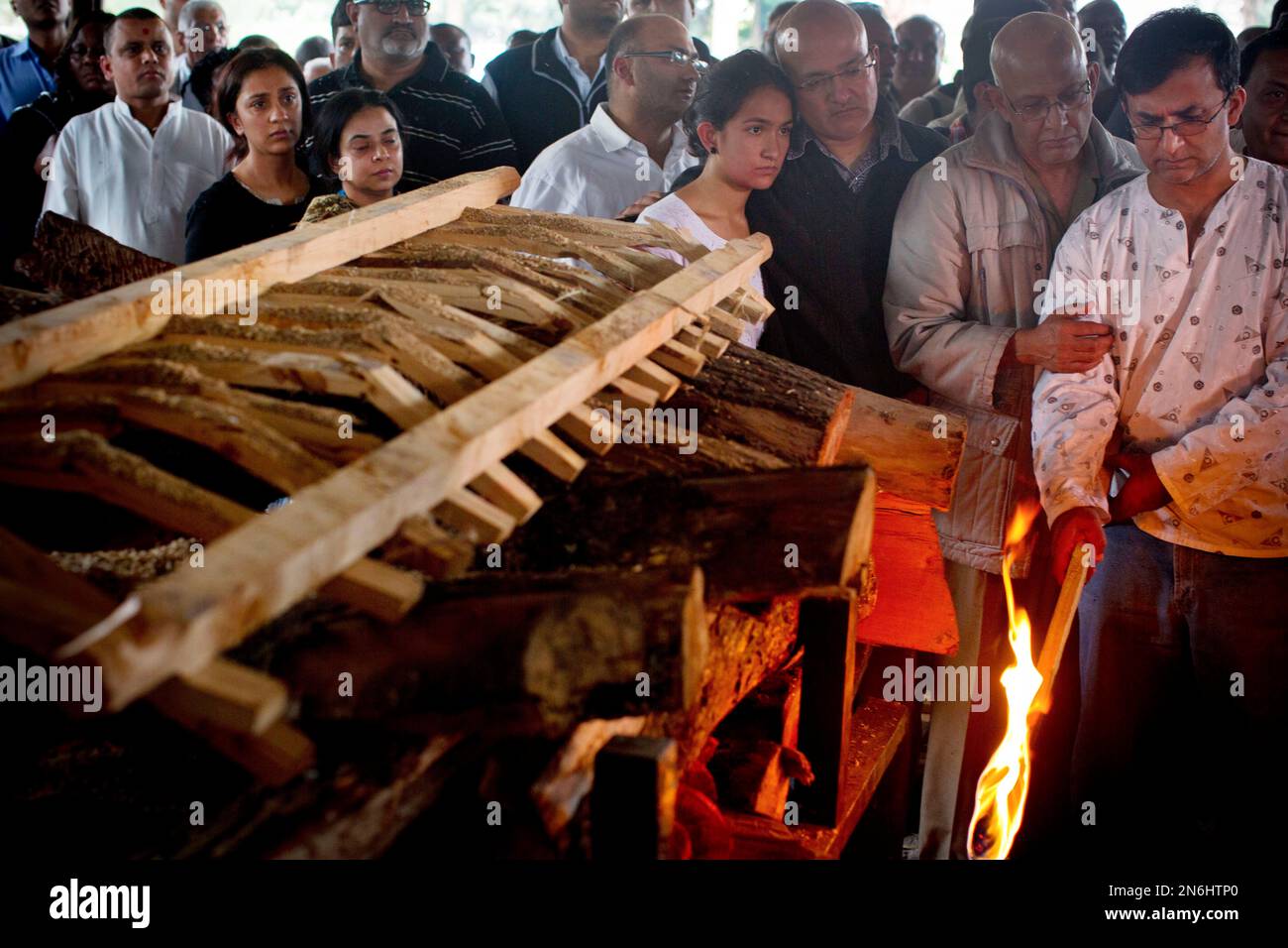 Ramesh Vaya, right, lights the funeral pyre of his wife Malti, who was