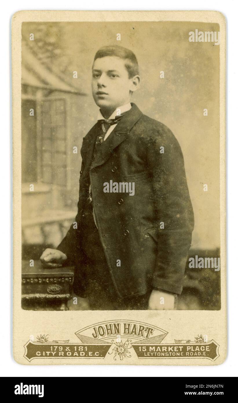 Original Victorian CDV (carte de visite or visiting card) studio portrait of good looking teenage boy, wearing a sack coat shirt or lounge suit as it is known in the U.K., with turned up collar and 'four in hand' tie. His surname is Harman. Probably a middle class lad as owns a watch on a fob chain - maybe a coming of age present. From the studio John Hart, 179.181 City Rd. & 15 Market Place, Leytonstone, London, U.K.. circa 1880's, early 1890's from studio dates. Stock Photo