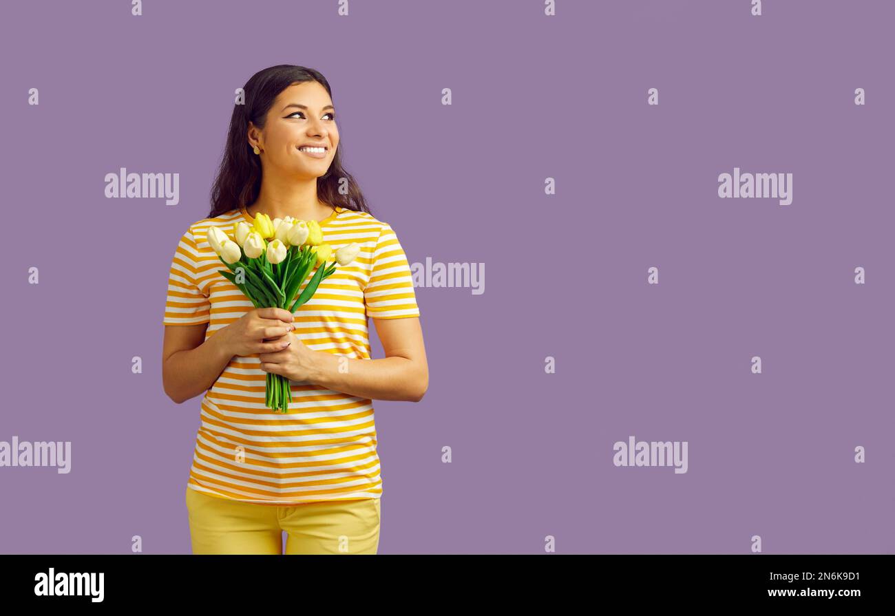 Caucasian woman with bouquet of yellow tulips on a purple background. International Women's Day. Bouquet of spring flowers. Empty place for Stock Photo