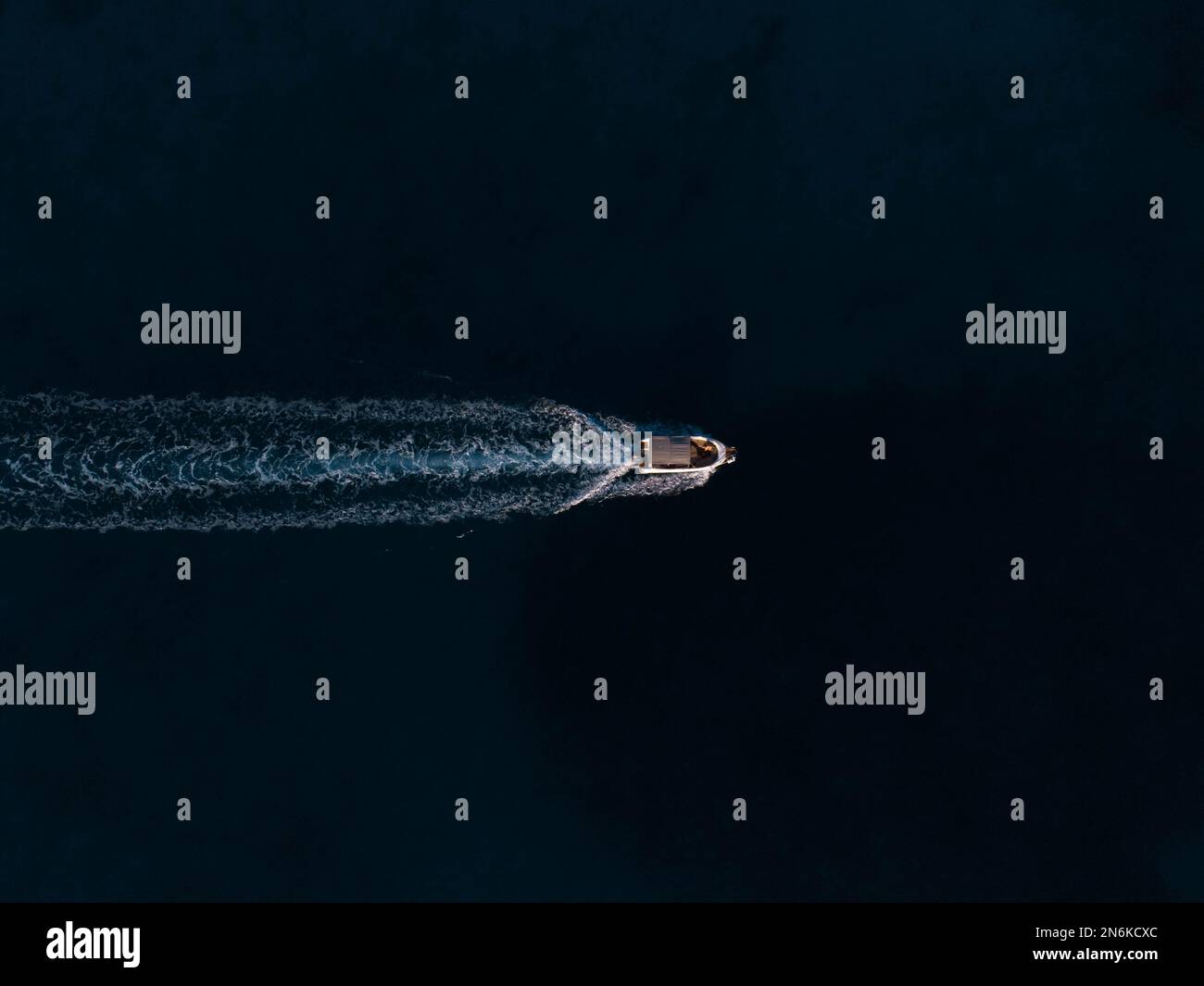 An aerial top view of a boat sailing in the water leaving a trail Stock ...