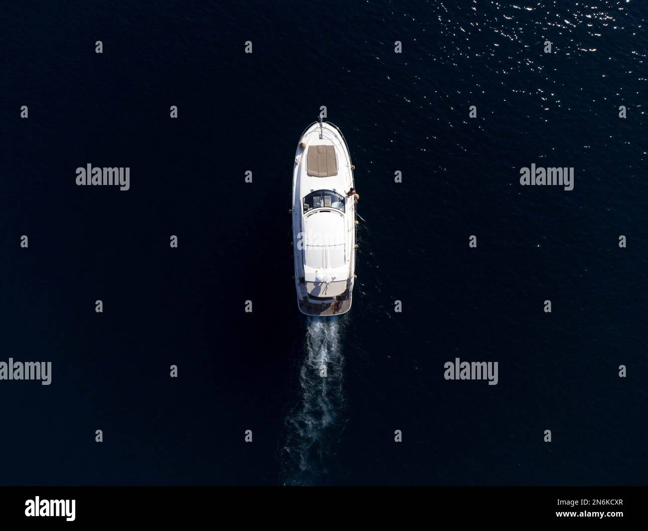 An aerial top view of a boat sailing in the water leaving a trail Stock ...