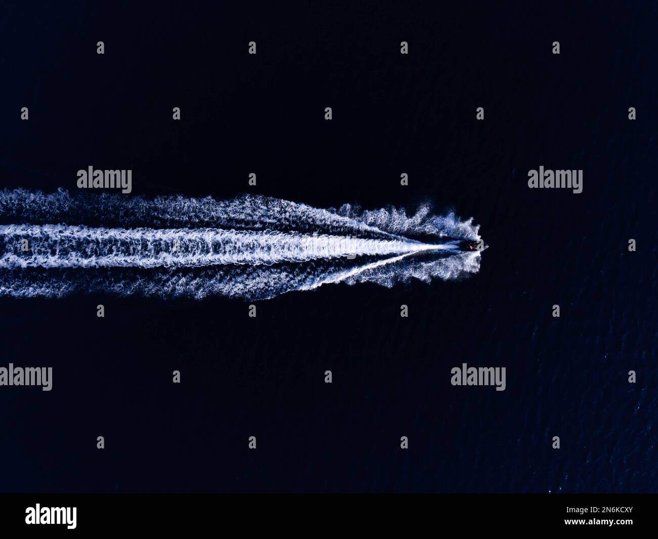 An aerial top view of a boat sailing in the water leaving a trail Stock ...