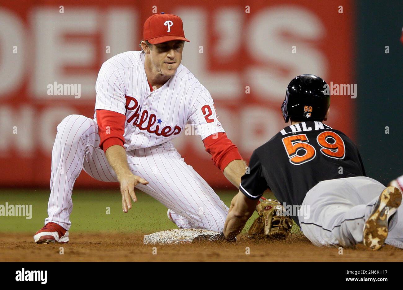 Miami Marlins' Ed Lucas, right, is tagged out by Philadelphia Phillies' Chase Utley while trying