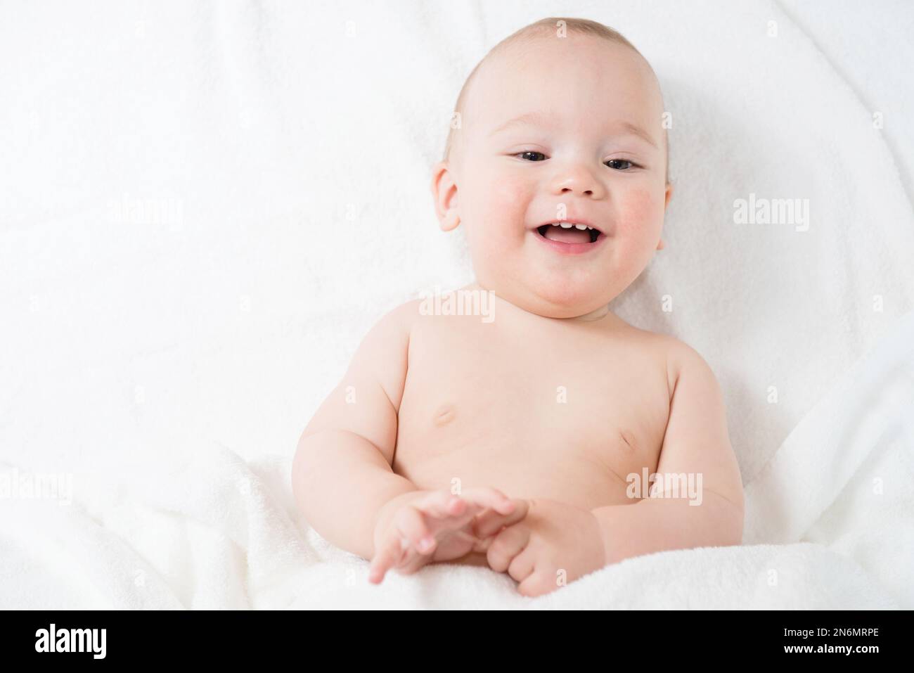Happy little baby in white towels after bath Stock Photo