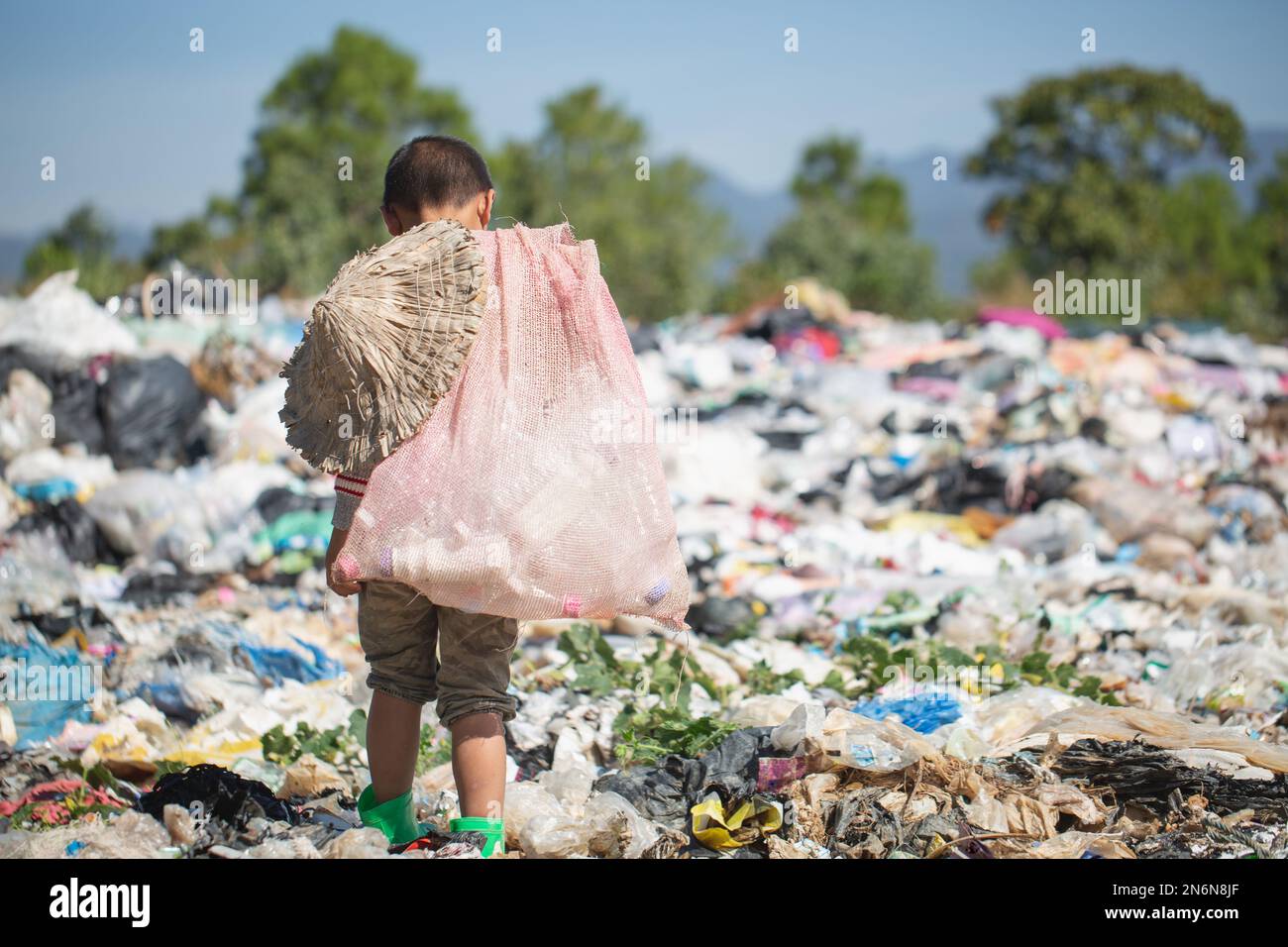 Poor boy collecting garbage in his sack to earn his livelihood, The concept  of poor children and poverty Stock Photo