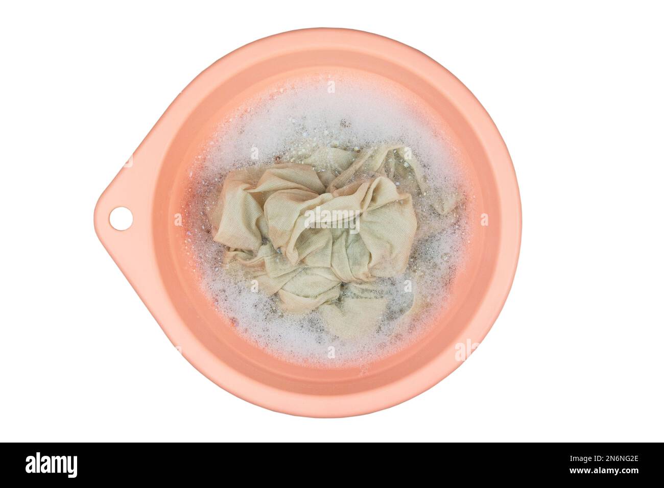 Washing clothes in a pink basin. Detergent with washcloths. Isolate on a white background. Top view. Stock Photo