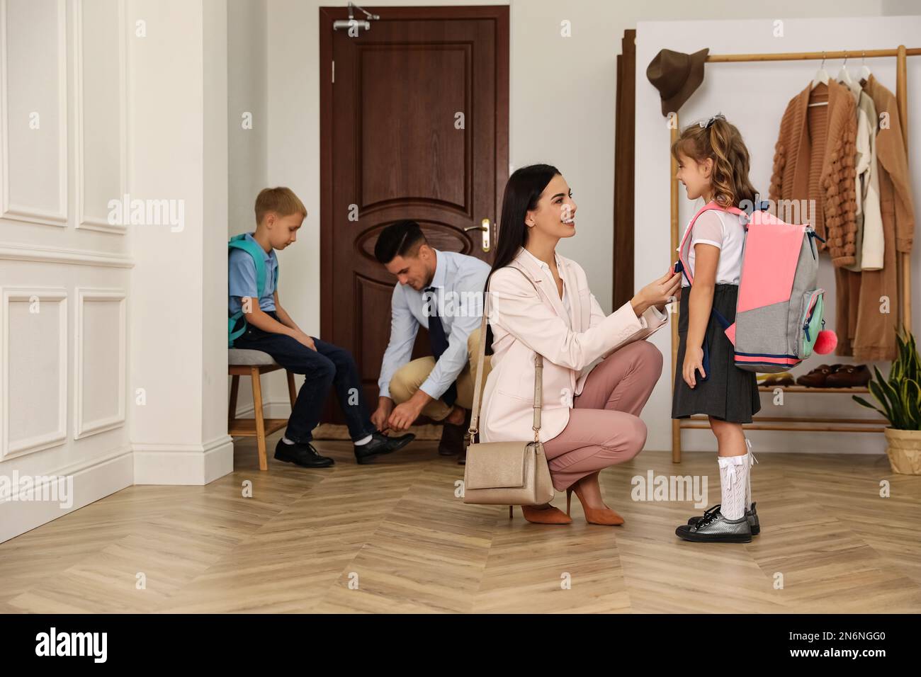 Parents helping their children get ready for school in hallway Stock