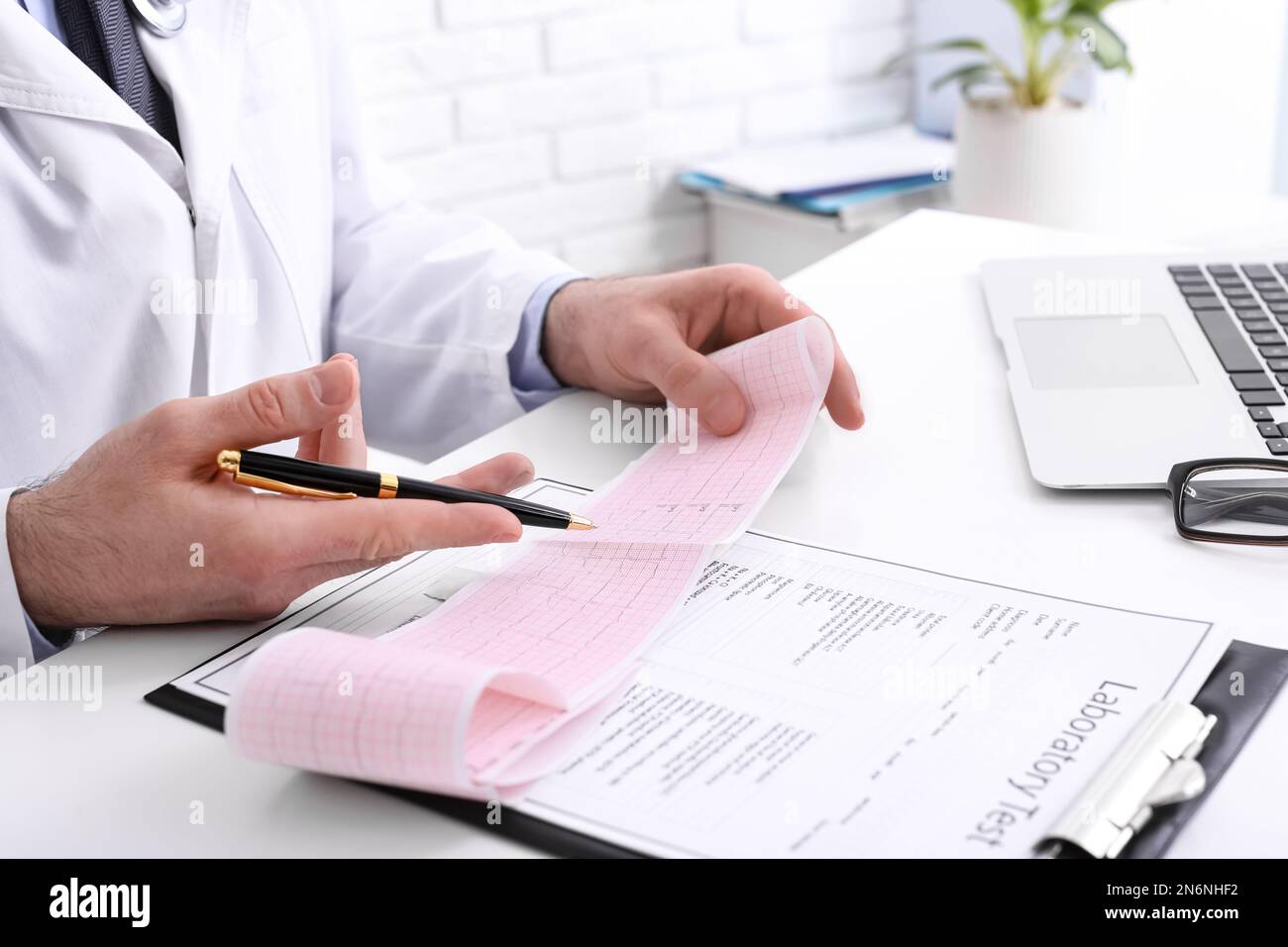 Doctor examining cardiogram at table in clinic, closeup Stock Photo - Alamy
