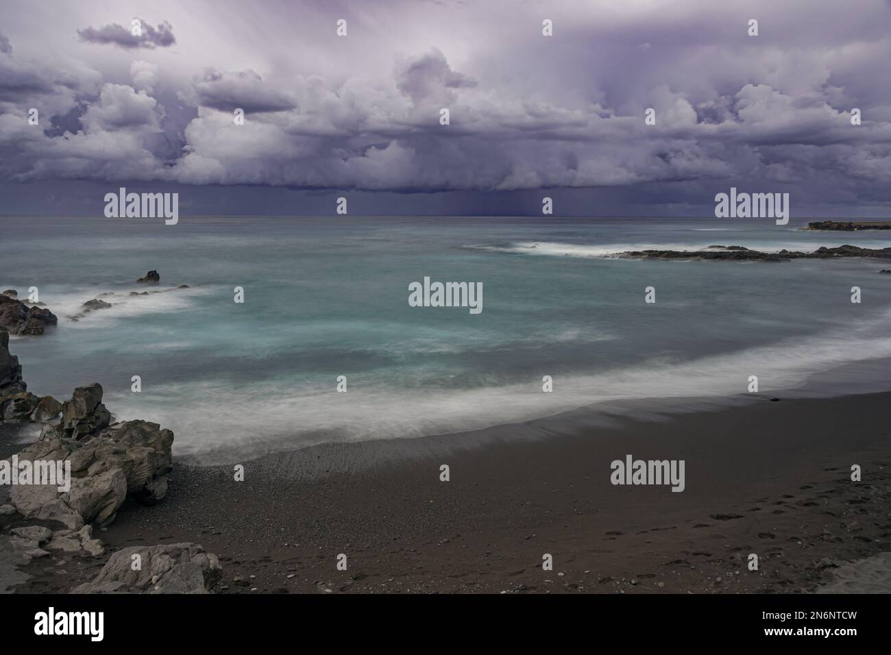 Very dark rain clouds over the Atlantic ocean, Playa Jardin beach, long exposure,  Puerto de la Cruz, Tenerife, Canary islands Stock Photo