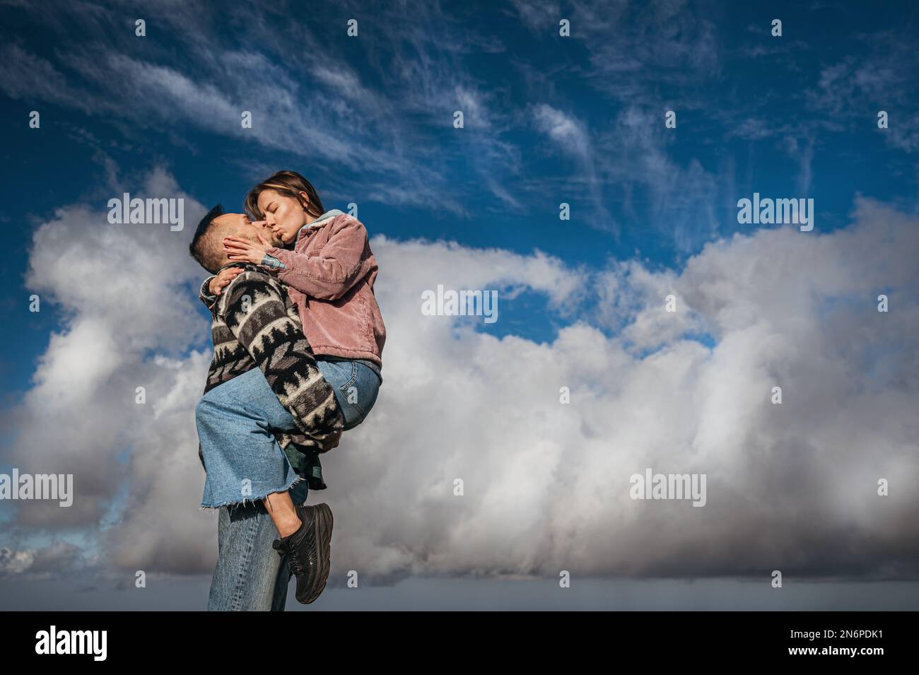Couple kissing, with a clear blue sky as the background Stock Photo